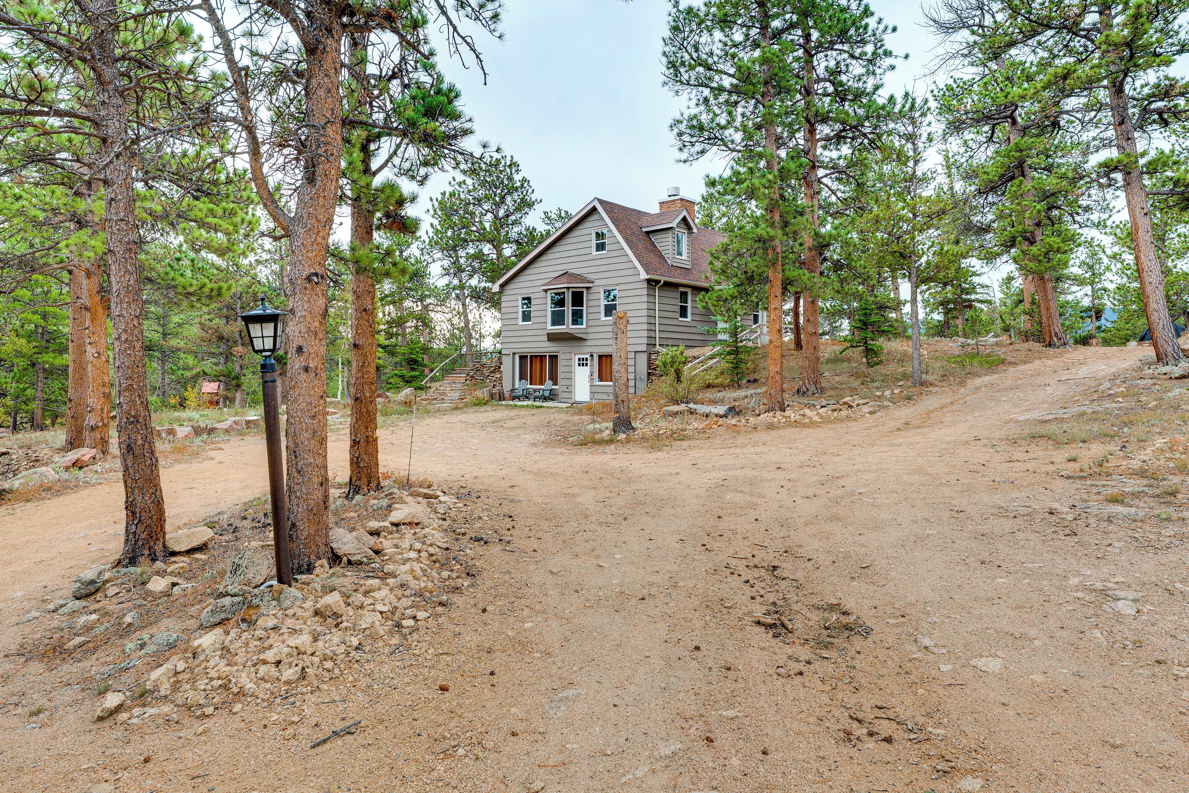 A two-story house with a visible front porch and a dirt driveway leading to it.