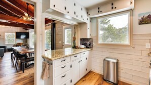 A modern kitchen with white cabinets, granite countertops, and a stainless steel trash can. - Quiet + Peaceful Home in Allenspark w/ Deck! (Allenspark)