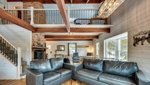 A spacious living room with a large leather sectional sofa, a fireplace, and a staircase leading to an upper level. - Quiet + Peaceful Home in Allenspark w/ Deck! (Allenspark)