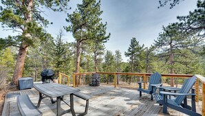 A wooden deck with a table and chairs, surrounded by trees. - Quiet + Peaceful Home in Allenspark w/ Deck! (Allenspark)