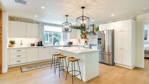 A modern kitchen with white cabinetry, a large island with stools, stainless steel appliances, and pendant lighting. - Naples Duplex Home w/ Private Pool & Lanai! (Naples)