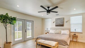 A bedroom with a bed, a bench, a ceiling fan, a window, and a plant. - Naples Duplex Home w/ Private Pool & Lanai! (Naples)