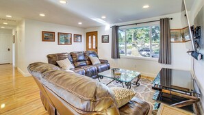 A spacious living room with leather sofas, a glass coffee table, and a flat-screen TV mounted on the wall. - Charming Arlington Home w/ Hot Tub & Fenced Yard! (Arlington)