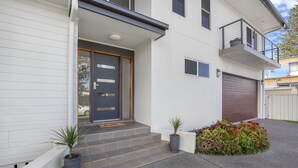 A modern two-story house with a front door, a small balcony, and a garage. - The ultimate property that you need to relax and unwind in Harrintgon (Harrington)