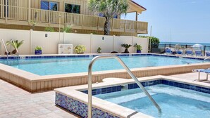Una piscina con borde de azulejos, una escalera metálica y una palmera.