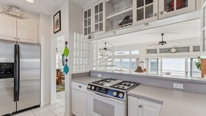 A modern kitchen with a built-in stove, stainless steel refrigerator, and white cabinetry. - Breathtaking Beach Front House 3 Bedroom Home by RedAwning (St. Augustine)