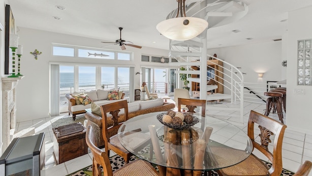 A spacious living area with a glass dining table, wooden chairs, and a modern staircase. - Breathtaking Beach Front House 3 Bedroom Home by RedAwning (St. Augustine)