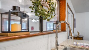 Una cocina moderna con un lavamanos de acero inoxidable, un cartel decorativo de bienvenida y un armario con puerta de vidrio.