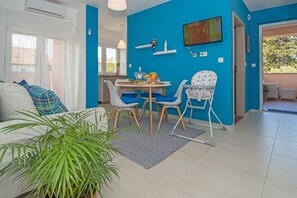 Relax in this stylish living space with a round dining table, comfortable sofa, and large plant.