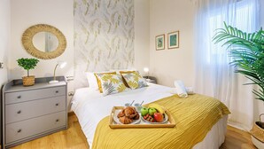 Un dormitorio ordenado con cama, mesita de noche y una bandeja con alimentos para el desayuno.