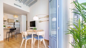 Una cocina moderna con horno empotrado, un comedor con mesa redonda y sillas, y un ventanal con vistas a la ciudad.