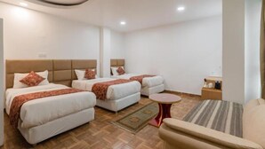 Una habitación de hotel con dos camas, una mesita redonda y un sofá.