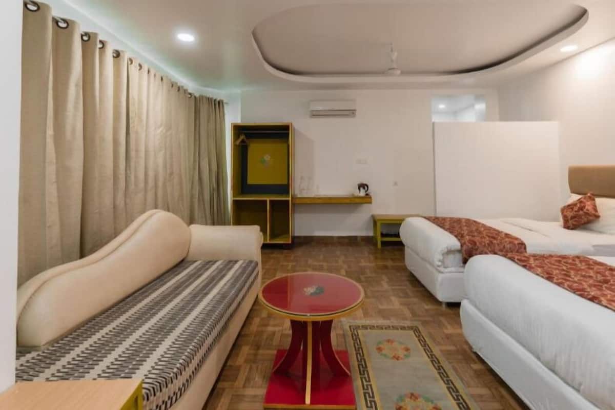 A hotel room with a sofa, a bed, a small table, and a wardrobe.