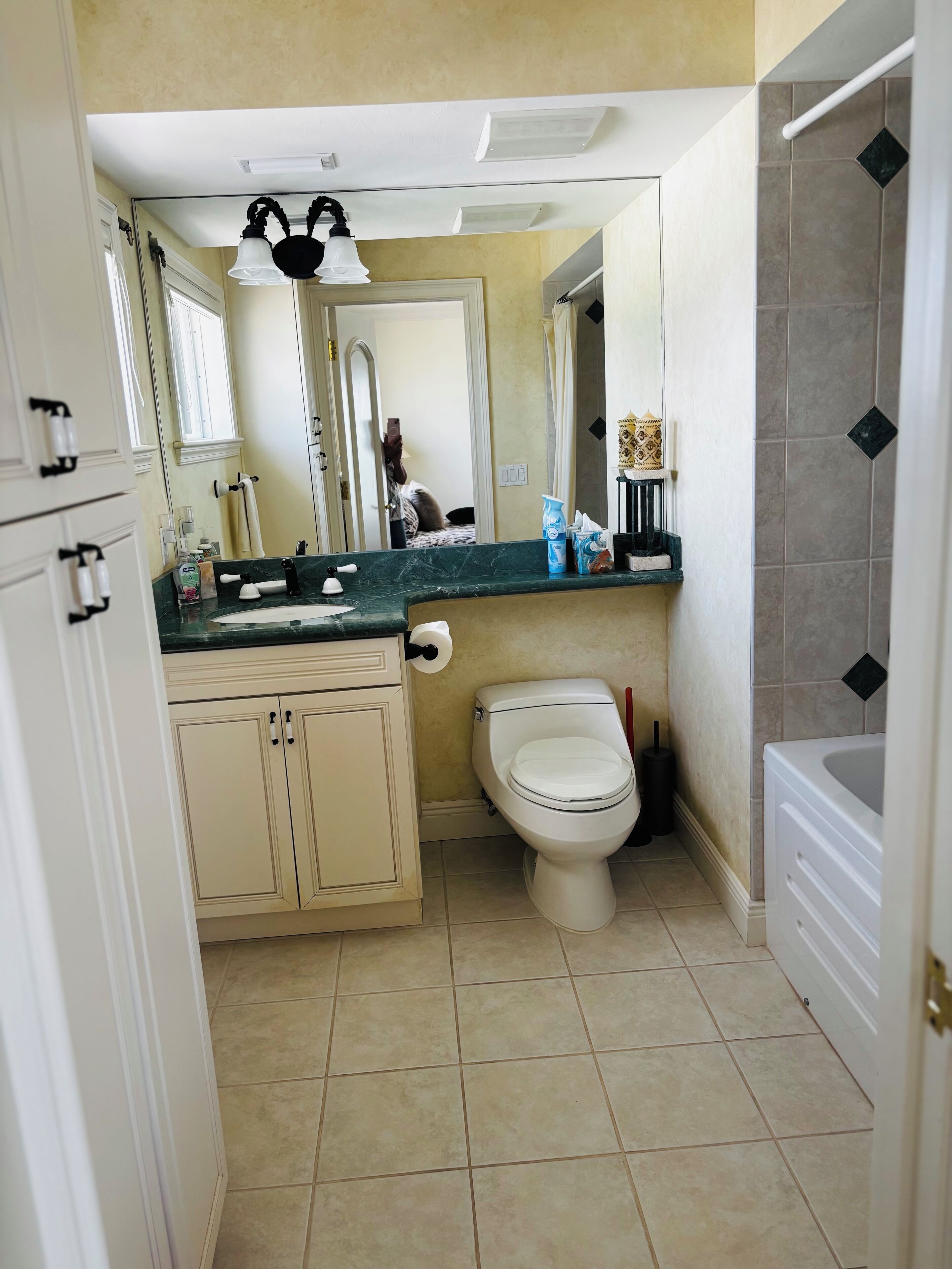 A bathroom with a toilet, sink, mirror, and a bathtub.