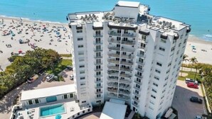 A high-rise hotel with multiple balconies, a pool, and a beach view. - Direct large, beachfront Condo, steps to Vanderbilt Beach, 3 bedroom, 3 bath. (Naples)