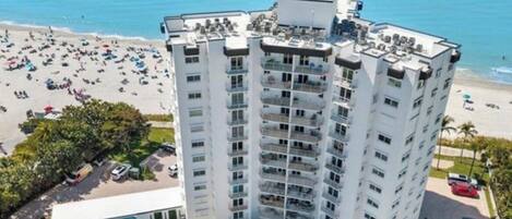 Un hotel moderno de gran altura con varios balcones, una piscina y vista al mar.