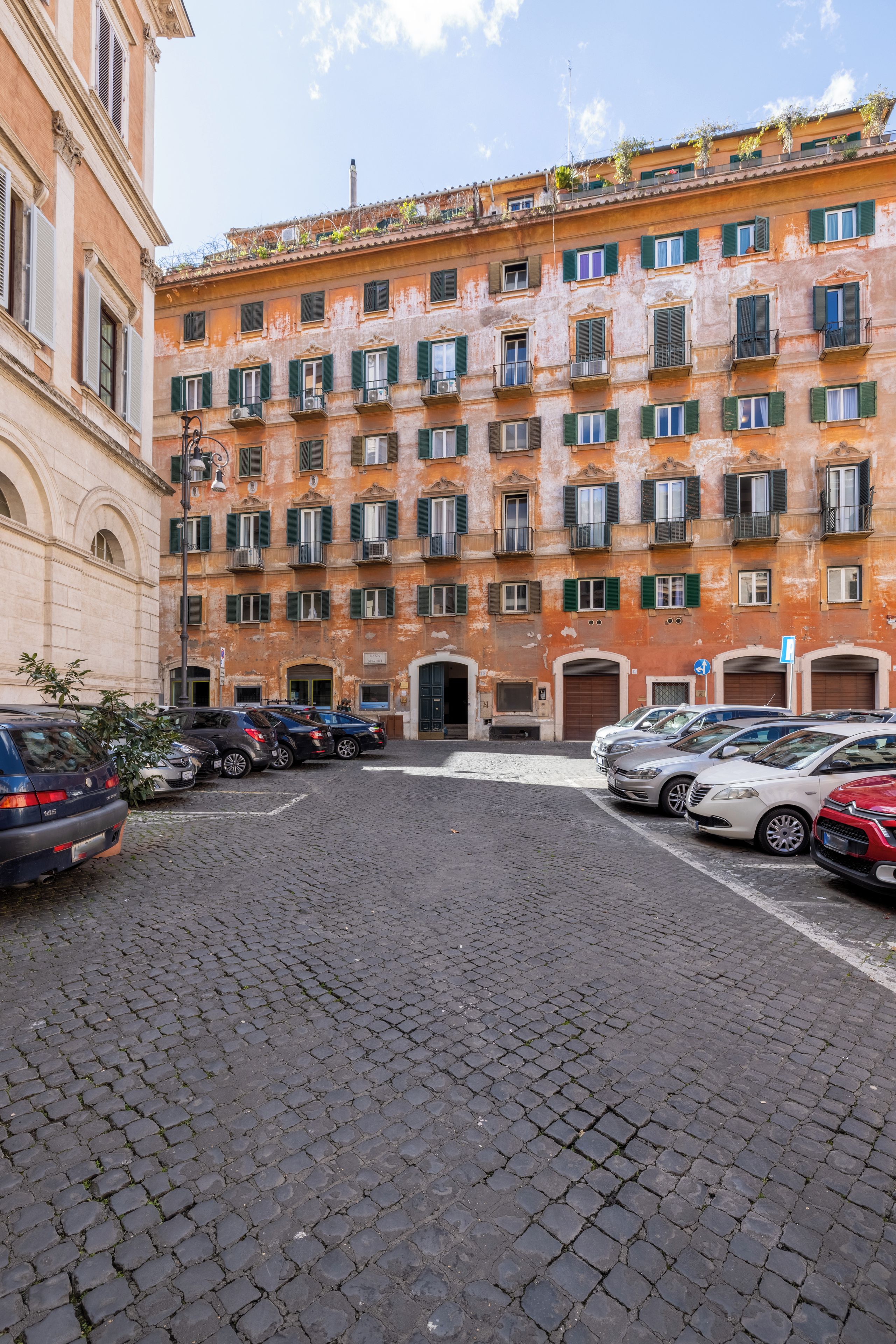 A courtyard with a row of parked cars and a building with multiple windows and balconies.