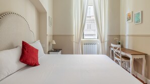 Et hotelværelse med en stor seng, et natbord, et træsidebord og et vindue med gardiner.