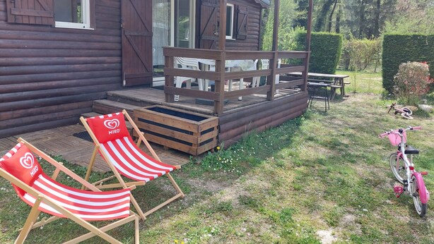 Una cabaña de madera con un porche, una mesa de picnic y una bicicleta.