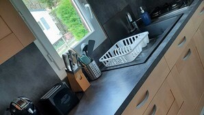 Una cocina moderna con armarios de madera, encimera negra y ventana con vistas al exterior.