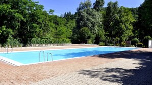 Una piscina rectangular con dos escaleras en un lado, rodeada por una zona pavimentada con diseño de ladrillo.