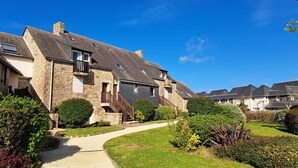 Une rangée de maisons en pierre, avec un chemin menant à l’entrée, le tout entouré de jardins bien entretenus.