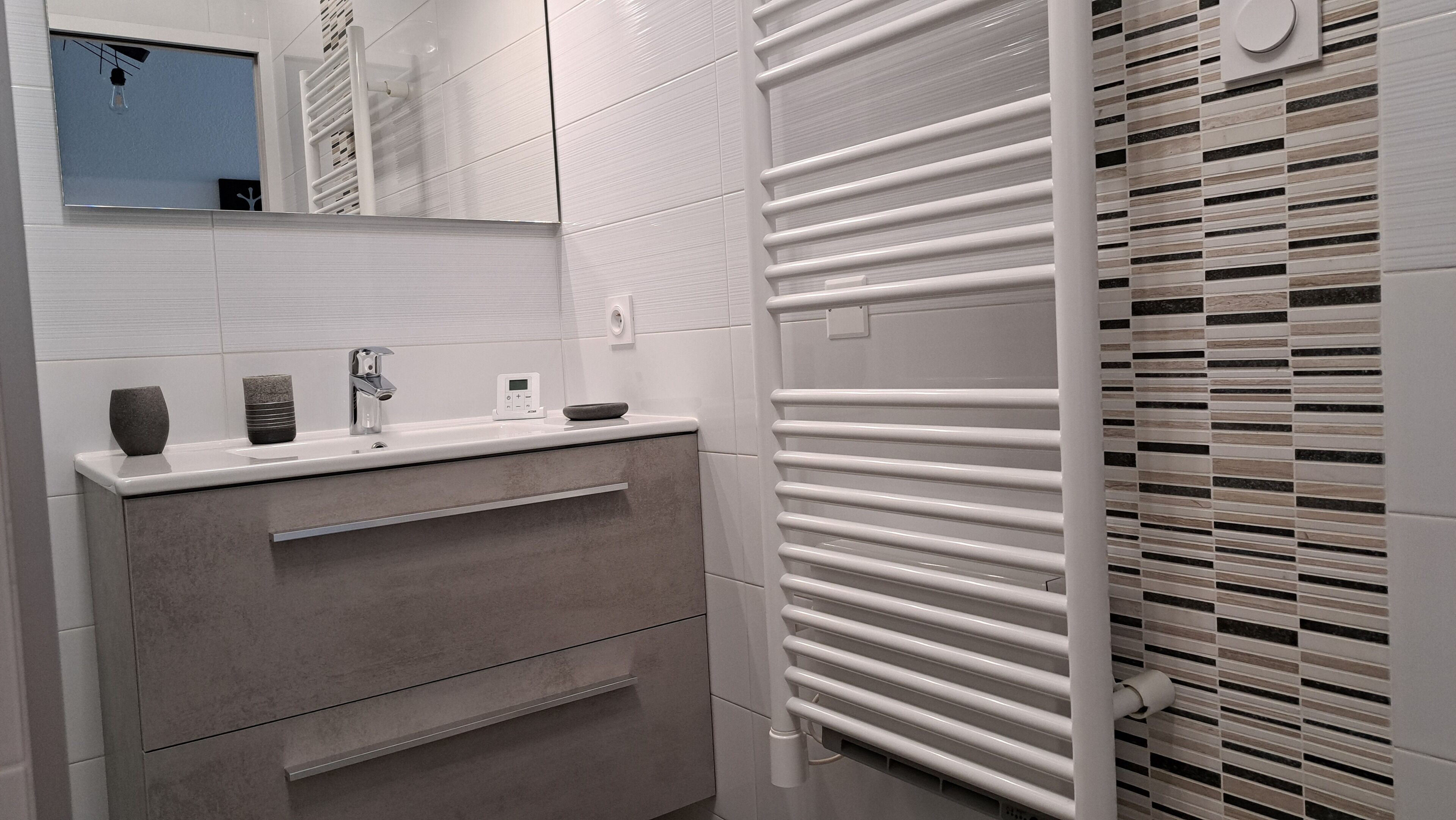 A modern bathroom with a white vanity, a towel rack, and a mirror.