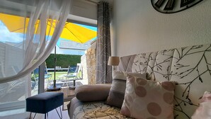 Une chambre à coucher avec un lit, des oreillers, une table de chevet et une fenêtre avec des rideaux.