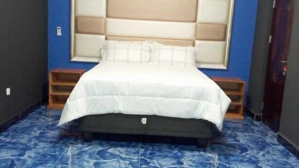 A bedroom with a large bed, a headboard, and a blue tiled floor.