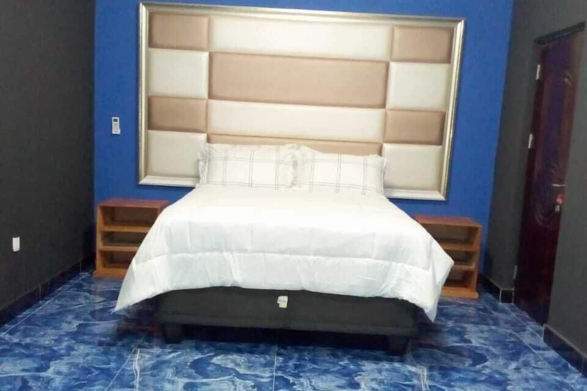 A bedroom with a large bed, a headboard, and a blue tiled floor.