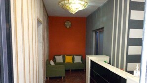 A hallway with a green sofa, a white console table, and a decorative ceiling light.