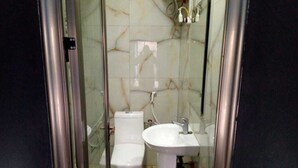 A bathroom with a glass-enclosed shower, a toilet, and a pedestal sink.