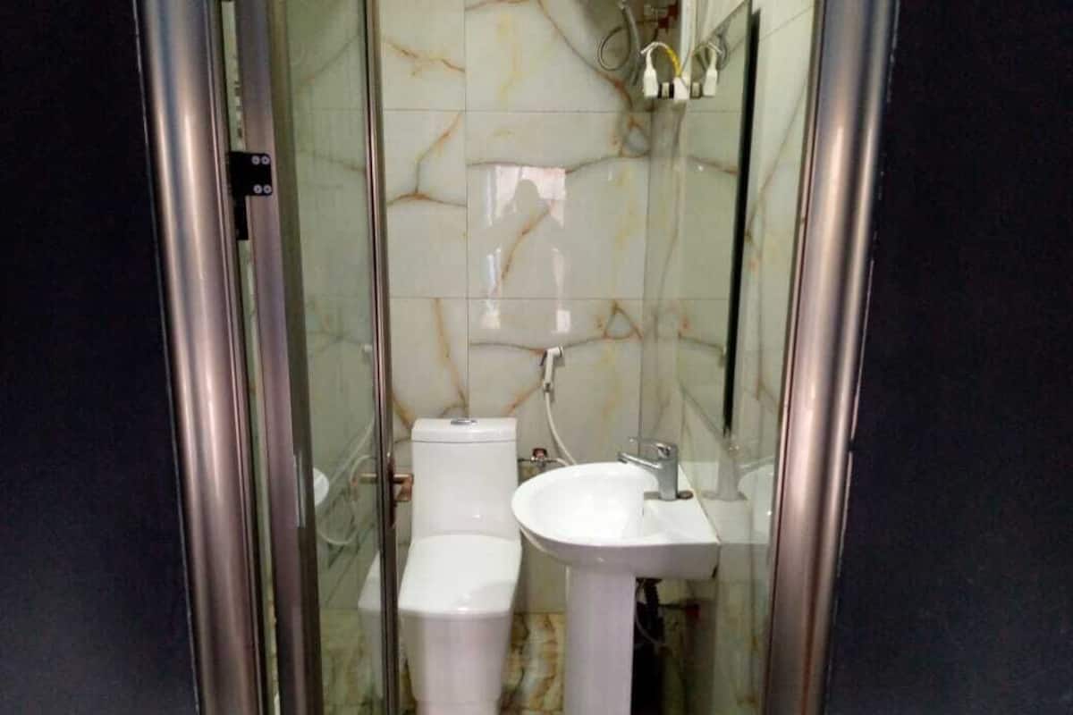 A bathroom with a glass-enclosed shower, a toilet, and a pedestal sink.