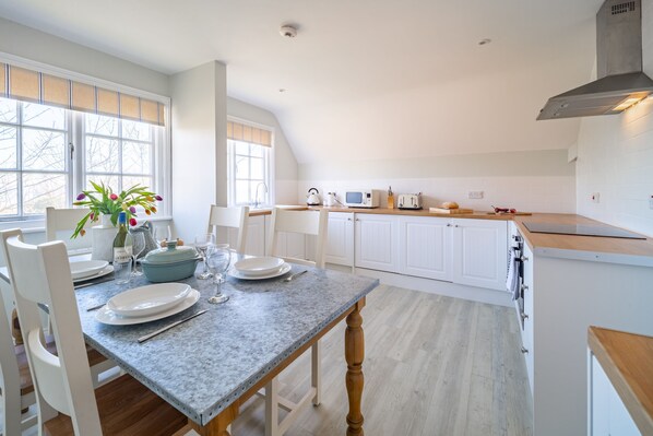 A modern kitchen with white cabinets, a granite countertop, and a dining area with a table set for four.
