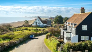 Una carretera costera con casas, un coche y vistas al mar.