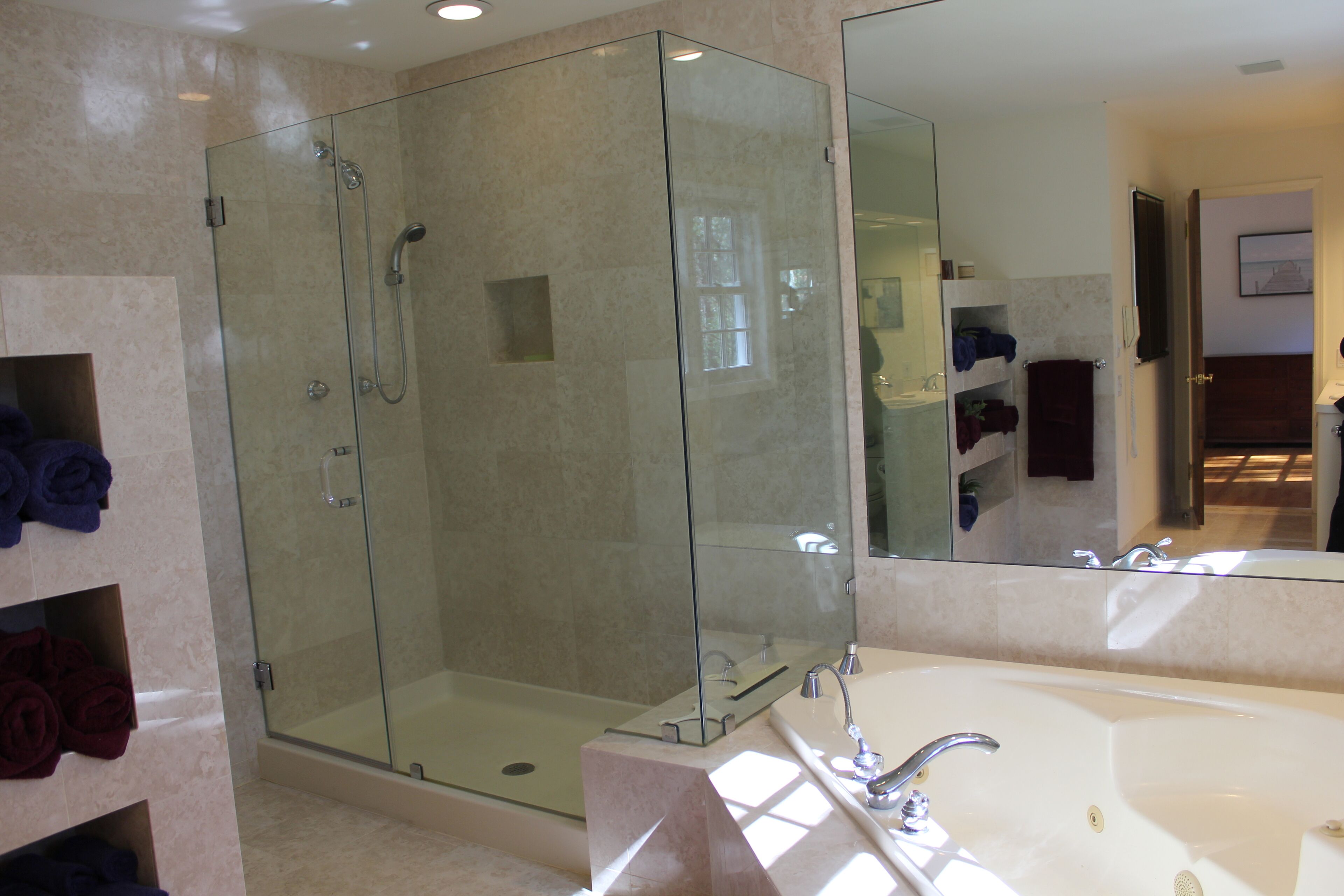 Une salle de bain moderne avec une douche à parois de verre, une grande baignoire blanche et des murs en marbre.
