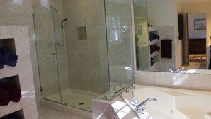 Une salle de bain moderne avec une douche à parois de verre, une grande baignoire blanche et des murs en marbre.