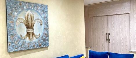 A modern living room with a blue sectional sofa, a wooden coffee table, and a decorative wall piece.