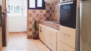 A kitchen with wooden cabinets, a stainless steel refrigerator, and a tiled backsplash. - Cosy Apartment Rabat center (Rabat)