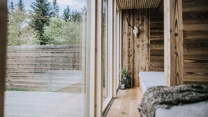 A wooden cabin interior with a large window, a wooden bench, and a deer skull on the wall. - Hotel Marvia (Schwarzenberg)