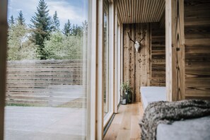 A wooden cabin interior with a large window, a wooden bench, and a deer skull on the wall. - Hotel Marvia (Schwarzenberg)