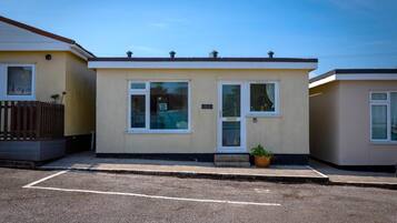 A single-story mobile home with a front door, two windows, and a small porch area.