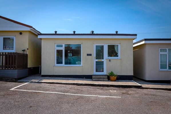 A single-story mobile home with a front door, two windows, and a small porch area.