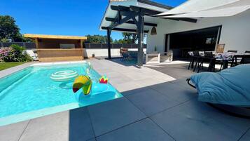 A swimming pool with a slide, a covered patio area, and outdoor seating.
