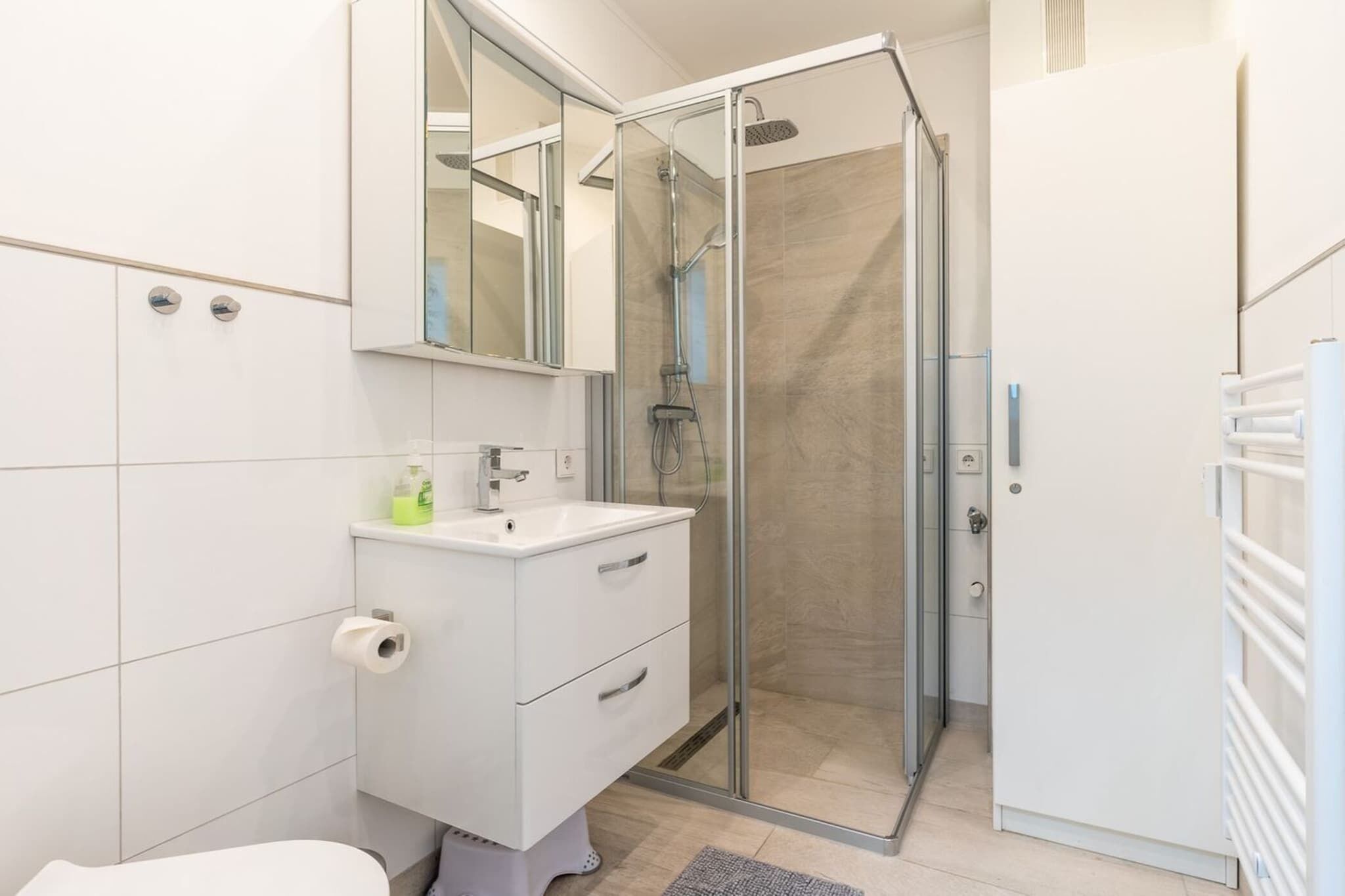 A modern bathroom with a glass shower enclosure, a white vanity with a mirror, and a toilet.