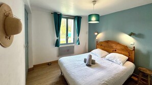 Ein Schlafzimmer mit einem hölzernen Bett, einem Vorhangfenster, einer Wandlampe und einem Hut an der Wand.
