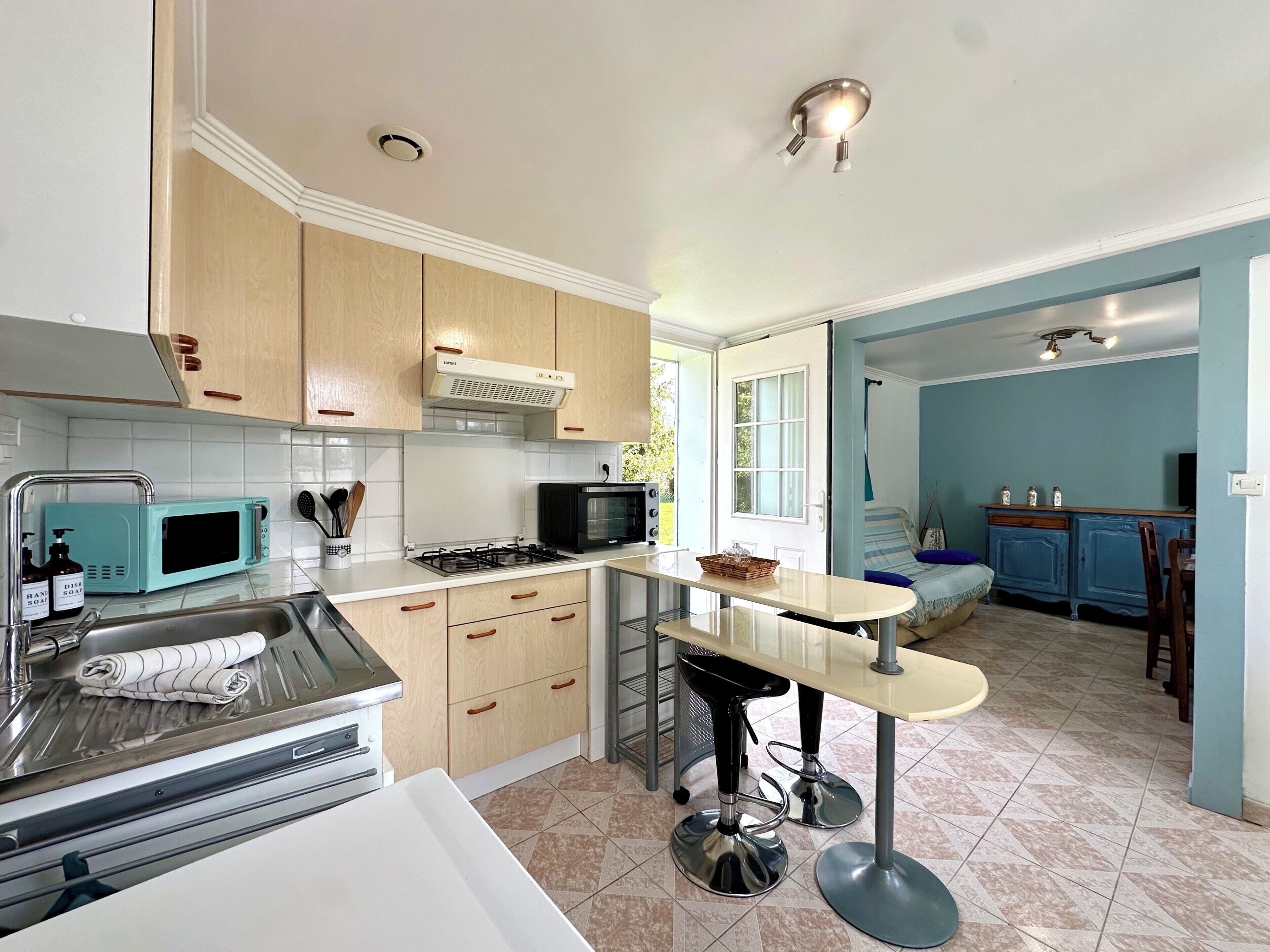 A compact kitchen with a microwave, stove, and sink. There is a small dining area with a table and chairs.