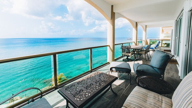 Un balcon avec vue sur l’océan, aménagé avec une table, des chaises et un banc.