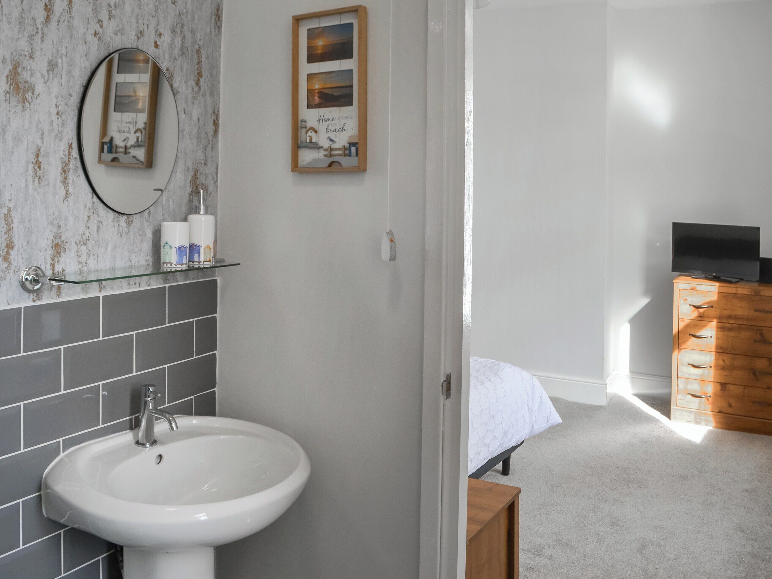 Ein Badezimmer mit einem weißen Waschbecken, einem Spiegel und einem gerahmten Bild an der Wand.