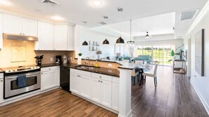A modern kitchen with white cabinets, a stainless steel stove, and a large island. - Golf Course View Condo w/ Pool Access, Near Disney (Reunion)